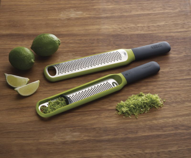 Ergonomic Joseph Joseph Zester with stainless steel blade and integrated wiper for easy zest collection and storage.