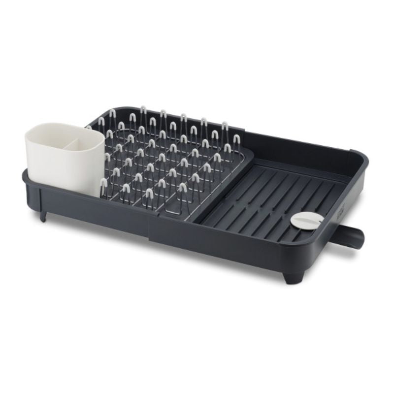 Expandable grey dish rack with non-scratch prongs, integrated spout, and movable cutlery drainer for efficient drying.