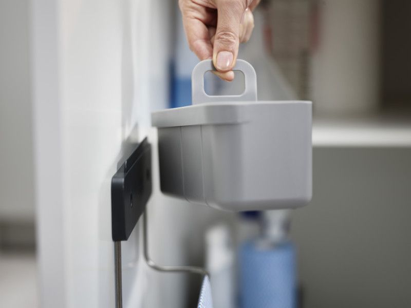 Joseph Joseph DoorStore In-cupboard Sink Tidy in Grey, featuring divided compartments and a stainless-steel rail for organizing cleaning supplies.